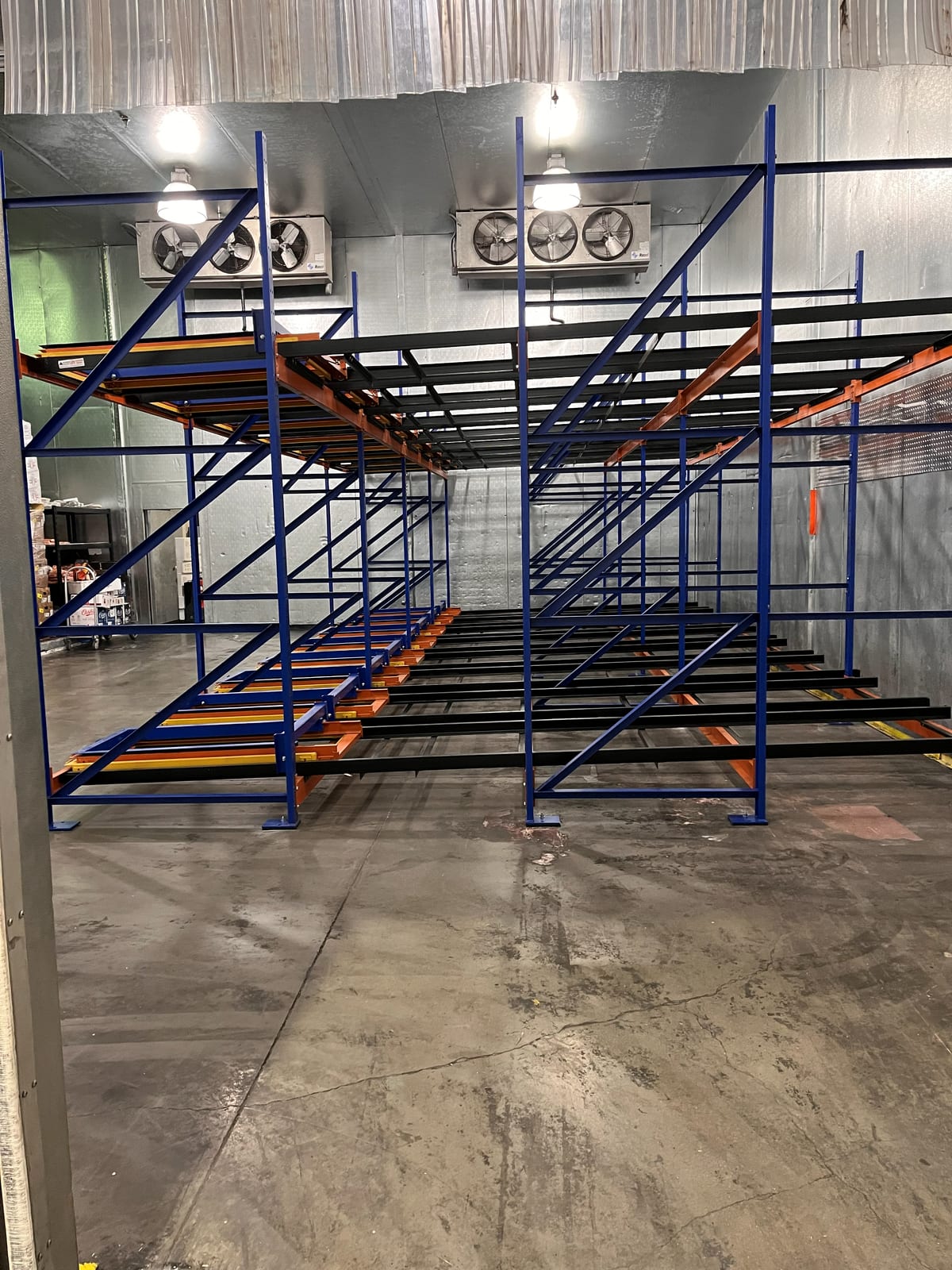 Empty 4-deep push-back rack bays two levels high installed inside a freezer room